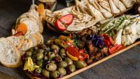 A spread of olives, bread, meat, and cheese.